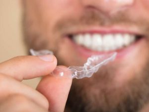 man holds clear aligners close up
