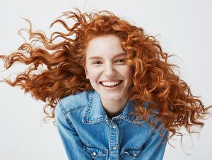 woman with red hair smiles with lingual braces