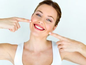 woman smiles and points at invisible braces behind the teeth