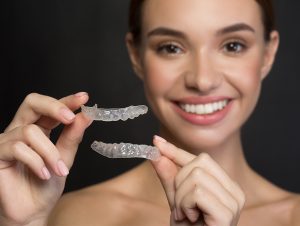 woman holds clear aligners in close up photo