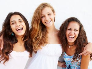 group of girls smiling, two eat before getting braces