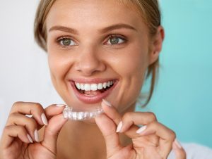 Smiling woman putting in clear aligner